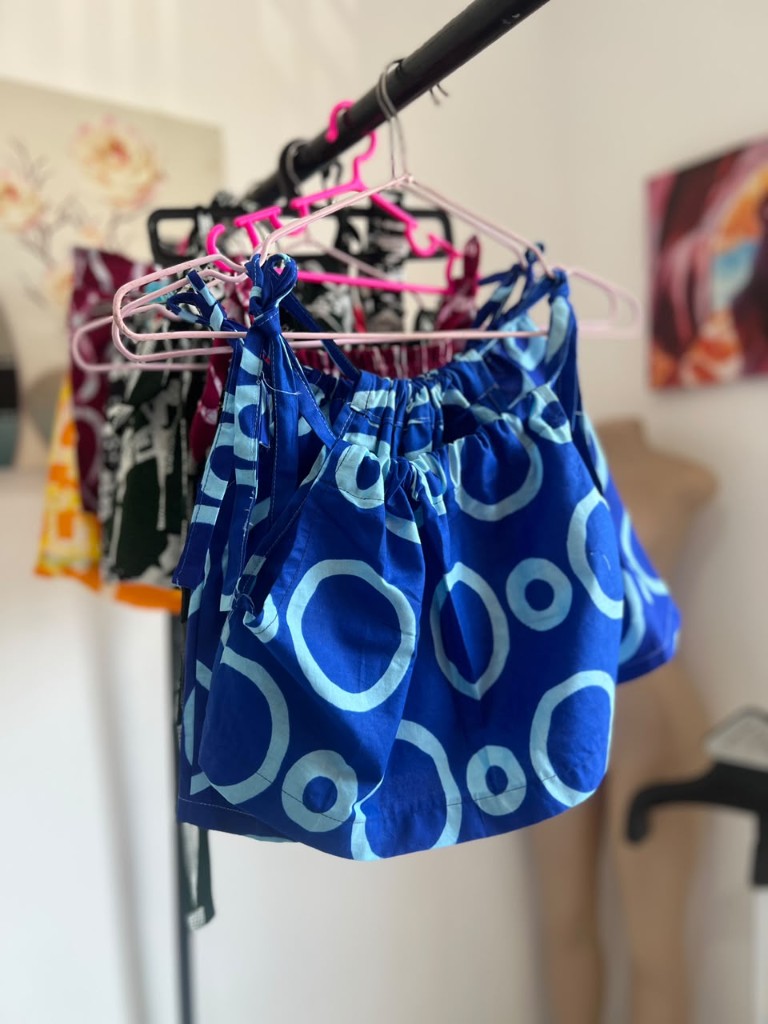 A child's indigo tie-shoulder top in a circle print, on a rail.
