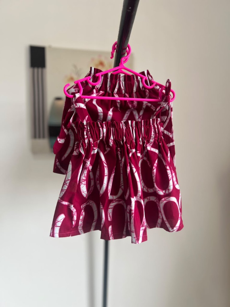 A child's magenta print top on a pink hanger.